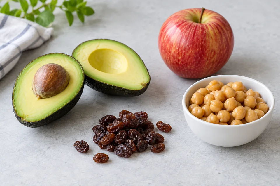 Avocado, an apple, raisins and chickpeas arranged on a table